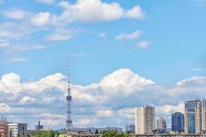 A tall TV tower against a blue sky in an urban summer landscape. photo