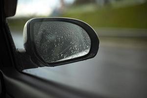 espejo retrovisor en coche. ventana del coche bajo la lluvia. detalles de transporte. foto