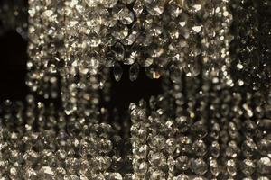 Texture of transparent glass in artificial light. Details of chandelier made of glass in dark. photo