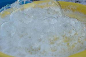 Soap foam for blowing bubbles on a yellow plate. photo