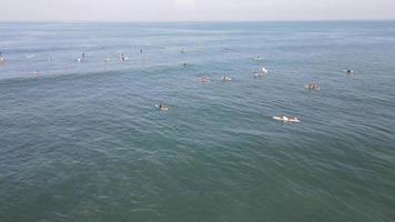 aereo Visualizza di persone fare surf su onde con tavole da surf quando vacanza nel Bali, Indonesia . video