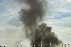 Fire in city. Black smoke in sky. Ignition of industrial zone. photo