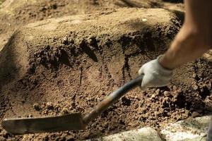 Undertaker strikes grave. Shovel and earth. Man is digging ground. Sand ramming. photo
