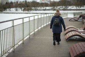 mujer camina por el paseo marítimo en invierno. parque de la ciudad. foto