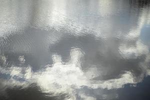 Texture of water. Reflection of clouds in water. Ripples on lake. photo