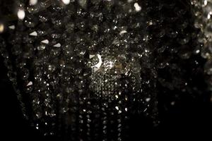 Texture of transparent glass in artificial light. Details of chandelier made of glass in dark. photo