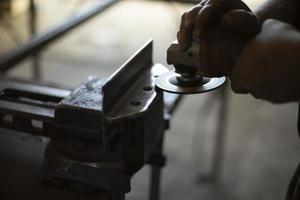 pulido de acero. trabajador muele metal. trabajo en garaje. herramienta eléctrica en la mano. foto