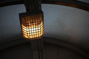 Lamp behind bars. Dim lamp light. Light system in tunnel. photo