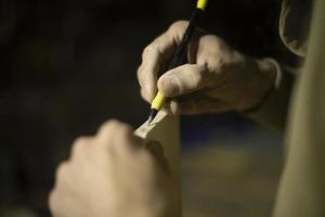 Guy is holding line and pencil. Man marks board. Carpenter measures size of tree. Details of work. photo