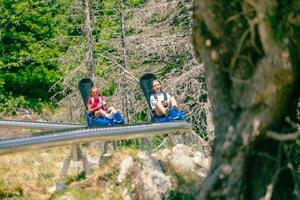 Girls ride a mountain roller coaster. Two mountain roller coasters. Tree ahead and a winding rail photo