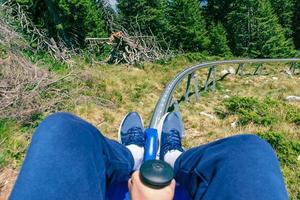 Mountain roller coaster first person. Guy is holding the brake lever. Railway line and trees in front photo