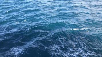 Calm blue sea waves with sunset light behind the ship. video