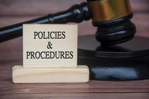 Policies and procedures text engraved on wooden block with gavel background. Policy and procedure concept photo