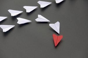 Red paper plane origami leading white planes on dark background. Leadership skills concept photo