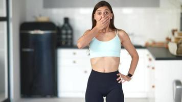 Young woman in workout clothes standing in a bright kitchen video