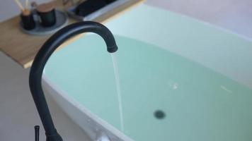 a água corre de uma torneira para encher um banho em um apartamento de layout aberto com luz natural video