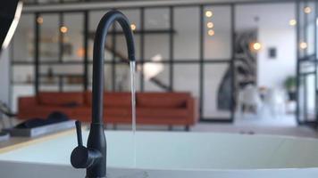 Water runs from a faucet to fill a bath in an open layout apartment with natural light video