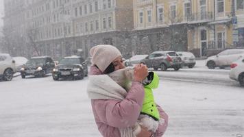 kvinna cuddles liten vit hund utanför i de snö både bär pösigt rockar video