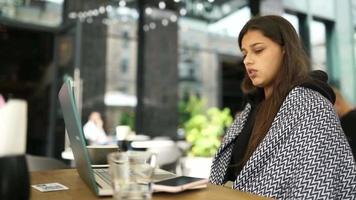 jong vrouw Bij een buiten koffie winkel tafel werken of studies met laptop video