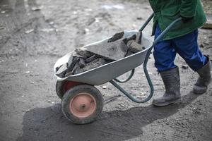 Builder removes broken stone. Man carries cobblestones in cart. photo