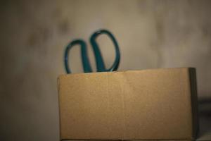 Cardboard box with scissors. Paper cutting tool. photo