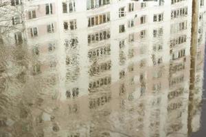 Building is reflected in puddle. Surface of water in city. photo