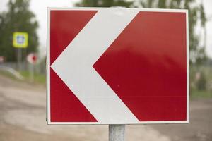 Sign sharp turn. Red road sign. Arrow pointer on road. photo