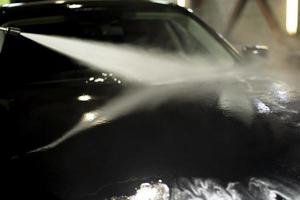 Car wash. Black car in car wash. Hot water jet. photo