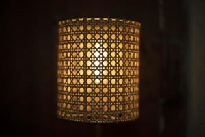 Lamp in dark. Wooden lampshade around incandescent lamp. photo