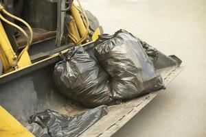 Black bag of garbage in tractor's bucket. photo