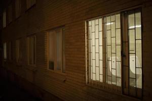 Window in building in evening. Grille on window at night. photo