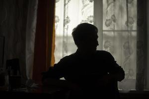 Silhouette of guy in room. Guy sits by window. Shadow of man. photo