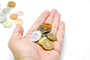 British currency coins on hand and blurry coins with isolate on white background and make with paths. photo