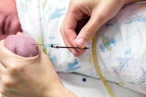 Image of nurse hands uses gradually stabbing medical needles at baby's hands to do a blood test. photo