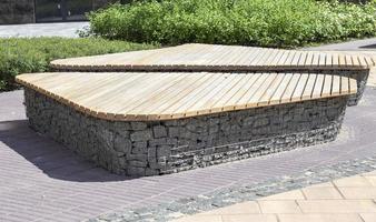 Wooden benches from gabion baskets with stones inside. Wood mounted on gabions. Benches of modern design. There is a recreation area. Detail of a low gabion wall with a wooden top. photo