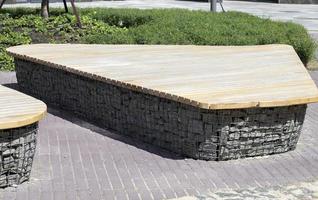 Wooden benches from gabion baskets with stones inside. Wood mounted on gabions. Benches of modern design. Detail of a low wood-topped gabion wall for use as a bench. photo