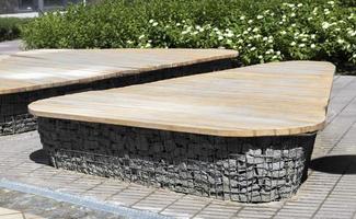Wooden benches from gabion baskets with stones inside. Wood mounted on gabions. Benches of modern design. There is a recreation area. Detail of a low gabion wall with a wooden top. photo