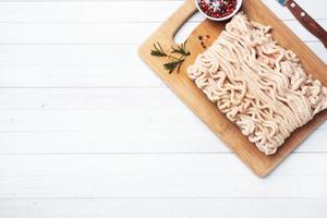 Minced chicken on a cutting Board with spices and lime. White table copy space. photo