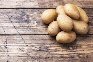 Several tubers of raw potatoes on a wooden background. Copy space. photo