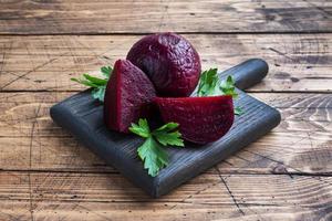 Boiled beets whole and cut on a cutting Board with parsley leaves on a wooden rustic background. Copy space photo