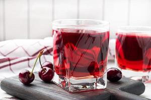 jugo de cereza en vasos de vidrio con bayas de cereza frescas. Fondo blanco. copie el espacio foto