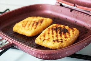Schnitzel fried on the grill pan. Two pieces of Cordon Bleu with ham and cheese in a pan. photo