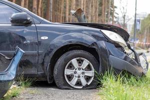 Black car after a terrible accident on the side of the road. Frontal and side impact. Life insurance. An accident without the possibility of recovery. Side view. Damage after an accident. photo