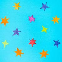 various stars cut from colour papers on blue paper photo