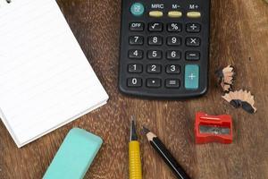 Notebook with a calculator and some pencils on a bench and green background photo