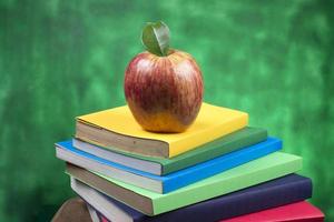 fruta de manzana encima de una pila de libros, en la parte posterior de las clases escolares. foto