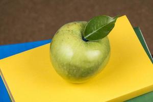 fruta de manzana encima de una pila de libros, en la parte posterior de las clases escolares. foto