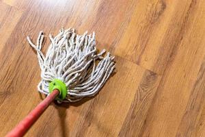 la fregona de cuerda está limpiando el suelo laminado de madera en casa foto