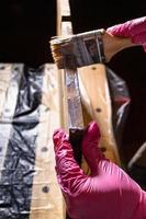 hand varnishes with brush the end of wooden board photo