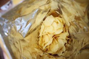 Potato chips in open snack bag close up photo